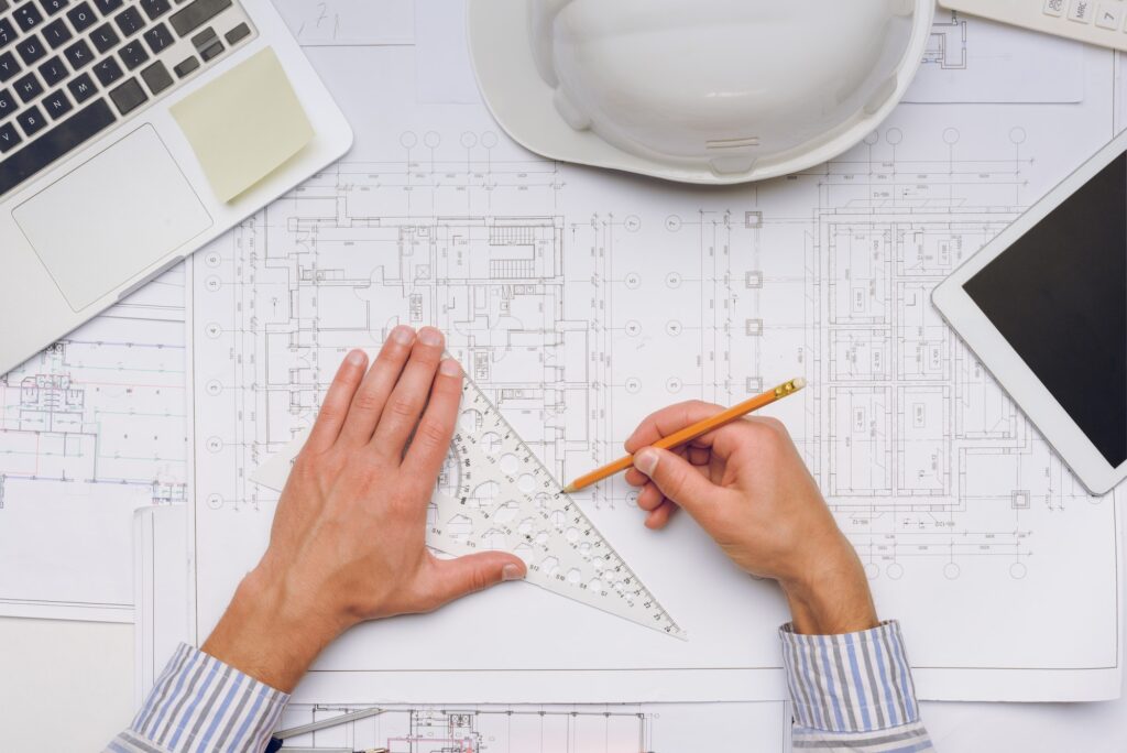 partial view of architect working with blueprints on new building design
